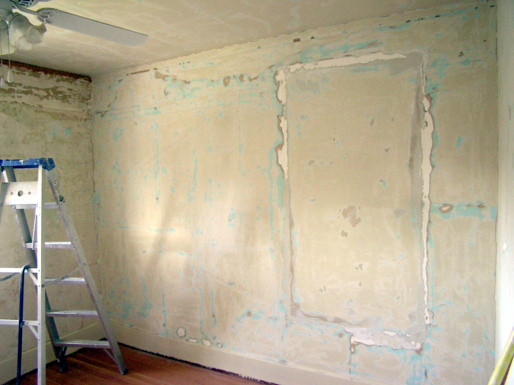 Room with sanded and patched walls mid-preparation with a ladder — wall prep before painting