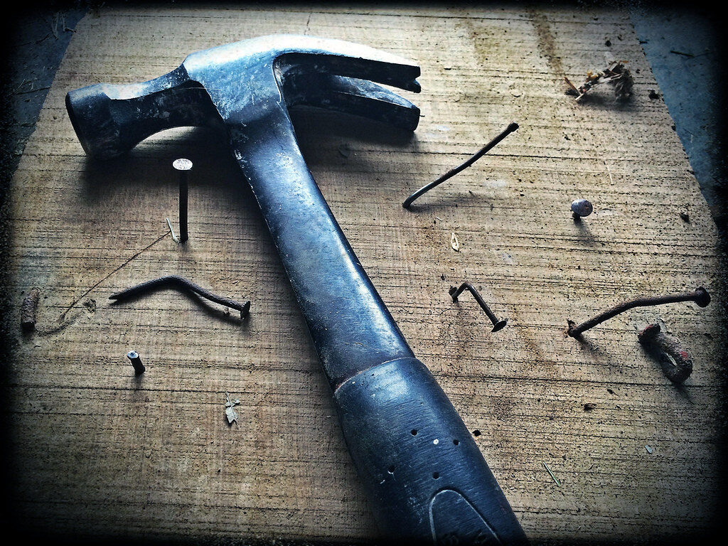 Well-worn claw hammer and nails on a timber workbench — household repairs in Rolleston Selwyn