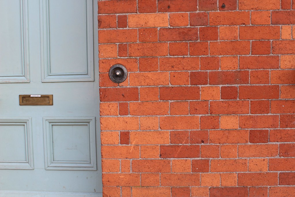 Red brick house wall beside a panelled front door with letter slot — brickwork in Selwyn District